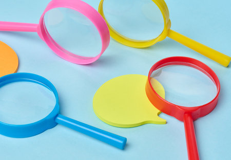 Multicolored plastic magnifying glasses on a blue background and paper notesの写真素材