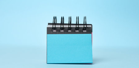 Notepad with empty blue sheets on a blue background. Copy spaceの写真素材