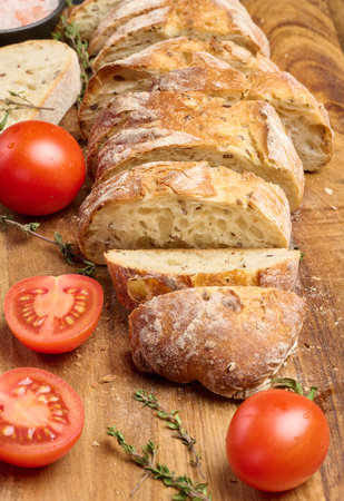 Sliced â€‹â€‹baguette and red cherry tomatoes on a wooden board