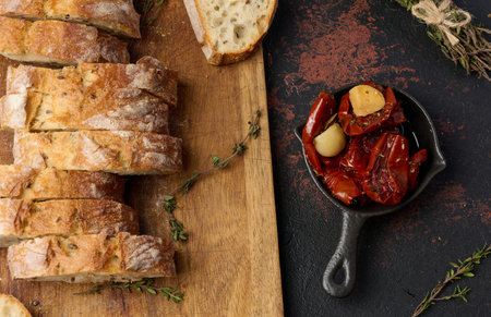 Sun dried tomatoes in a bowl and sliced â€‹â€‹ciabatta pieces on the table, snack