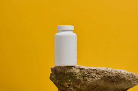 White plastic medicine jar on stone, yellow background. Mock upの写真素材