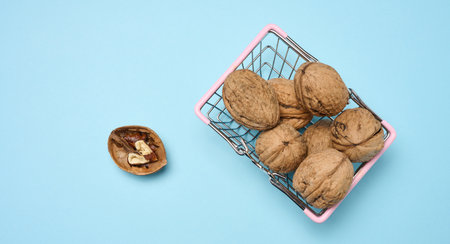 Walnut fruits in an iron basket on a blue background, top view