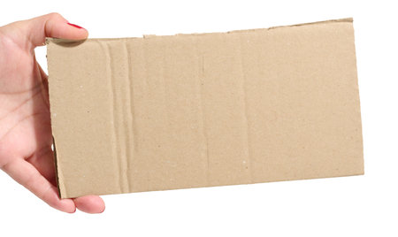 Female hand holding a piece of brown cardboard on isolated background, space for copyの写真素材