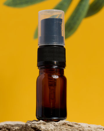 Brown glass bottle with dispenser stands on stone, yellow backgroundの写真素材