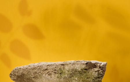 Stones on yellow background, stage for advertising and product demonstration. Shadows from leavesの写真素材