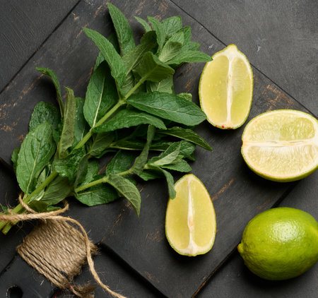 Bunch of fresh green mint on wooden board and lime wedges, top view. Cocktail ingredientの写真素材