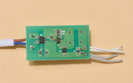 Green electronic board with components and some wires placed on beige background. Top viewの写真素材