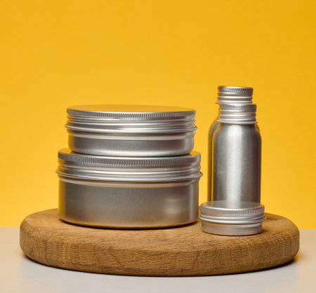 Aluminum jars and bottles for cosmetics and care. Minimalistic packaging on a bright yellow...