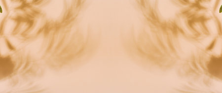 Blurred shadows of palm leaves are cast across a solid light brown background, creating a subtle and...