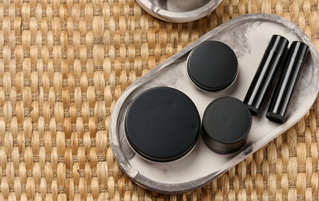Black metal cosmetic jars and tubes on a decorative tray. Minimalism, skin care, stylish beauty...