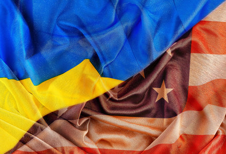 The flags of Ukraine and the United States intersect on a textured fabric, symbolizing union, support, diplomacy and international relations between the countries.の写真素材