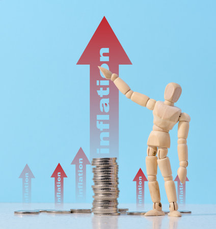 A wooden mannequin points to a rising red arrow with the word inflation against a stack of coins....