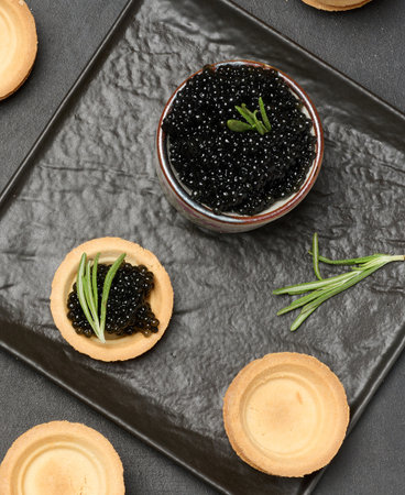 Black caviar in a round tartlet and a black bowl, a delicious appetizerの写真素材