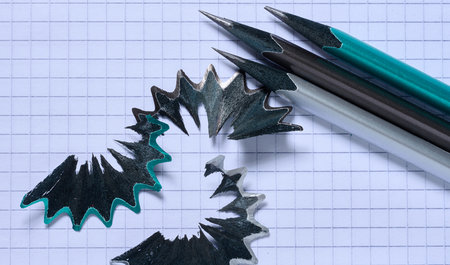 Wooden pencil shavings and a pencil lying on a paper background, top viewの写真素材