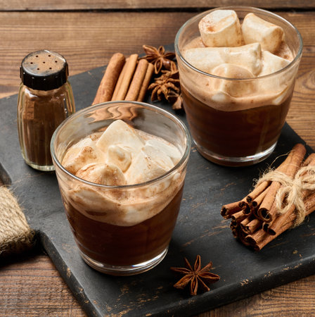 Two glasses of hot chocolate with fluffy marshmallows on a slate board. A close-up of the winter drinkの写真素材