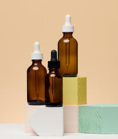 Various glass bottles with pipettes containing cosmetic serums or oils. Beige backgroundの写真素材