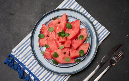Bright, juicy watermelon slices with mint leaves served on a plate. Top view.の写真素材