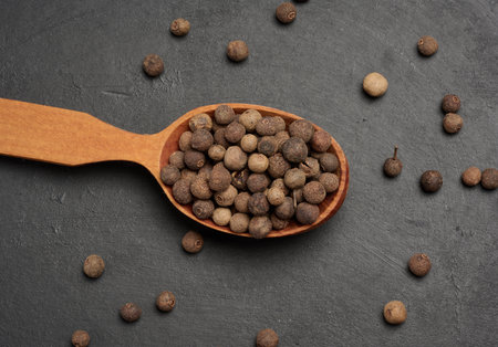 Allspice berries in a wooden spoon
