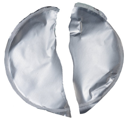 Close-up of a crumpled round foil yogurt lid on an isolated background.の写真素材