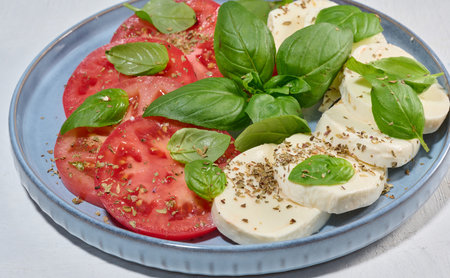 Classic Caprese salad with sliced â€‹â€‹fresh tomatoes, mozzarella and basil leaves on a...
