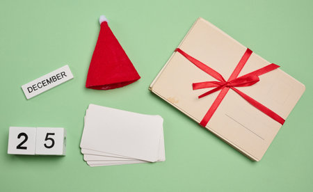 Set of Christmas elements: red Santa hat, cards, blank cards and calendar cubes with the date December 25 on a green background.の写真素材