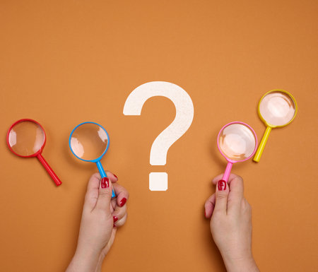 Female hands holding a plastic magnifying glass and a question mark. Search for solutions, reportの写真素材
