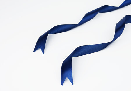 Blue satin ribbons arranged parallel in the upper right corner of the frame with wavy ends, isolated backgroundの写真素材