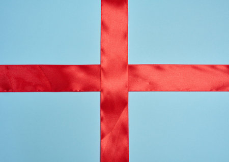 Two wide red satin ribbons intersecting at right angles in the center of the frame, blue background.