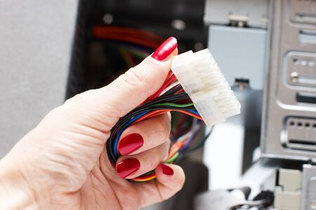 Woman hand assembles computer cable into system unitの写真素材