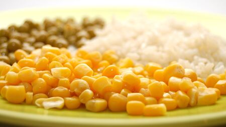 Green plate with vegetarian food: rice, corn, peasの写真素材