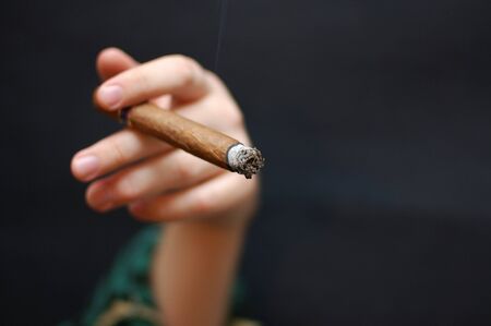 Man hand holds cuban cigar with smokeの写真素材