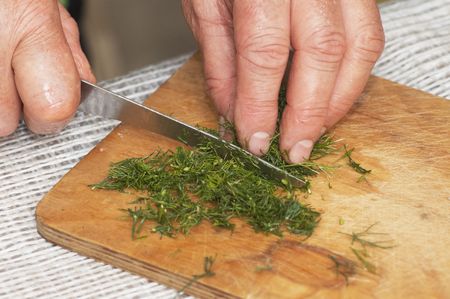 Cooking: woman hands cutting dill by kitchen knifeの写真素材