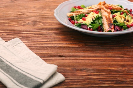Salad with fried salmon, avocado and pomegranate seeds. Low fat healthy eating concept.