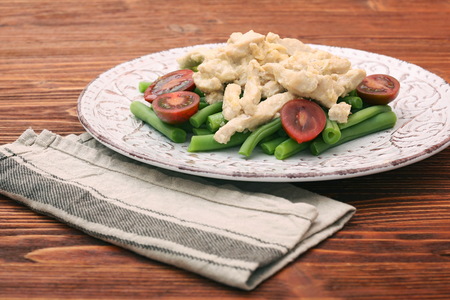 Tasty green beans with chicken meat and creamy sauce on wooden background