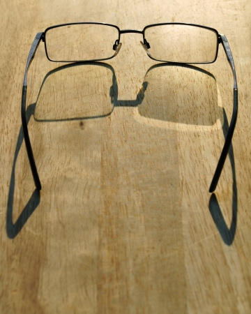 Glasses laying on sunlit wooden tableの写真素材