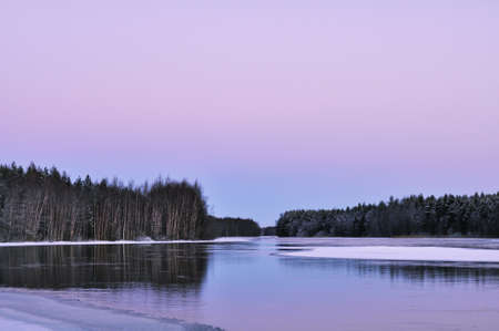 A landscape with winter river partially covered with ice in twilightの写真素材