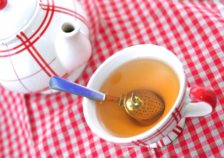 A cup of tea and a teapot on a red checked clothの写真素材