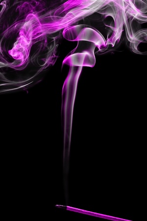 Pink smoke coming up from an incense stick over a black backgroundの写真素材