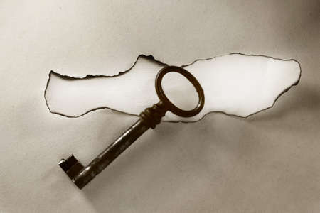 old key isolated on vintage paper backgroundの写真素材