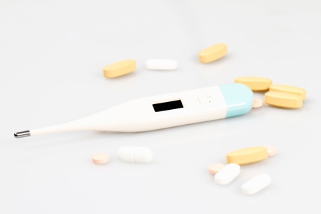 Yellow pills and thermometer on a white backgroundの写真素材