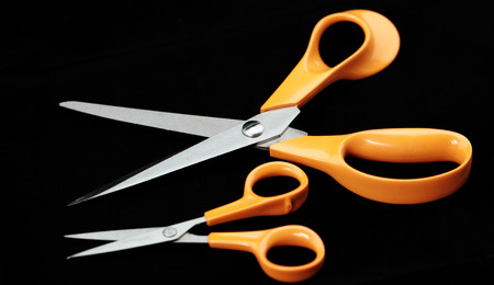 Photo of an orange scissors with black backgroundの写真素材