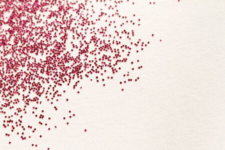 Red glitter on light background - macro photo