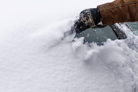 Man scraping snow and ice from car windowの写真素材