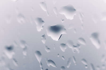 Blue background with natural water drops on glassの写真素材