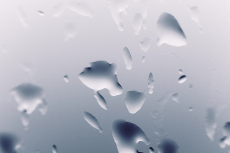 Blue background with natural water drops on glassの写真素材