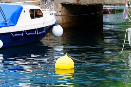 Blue and white motorboat with yellow buoy - detail photo