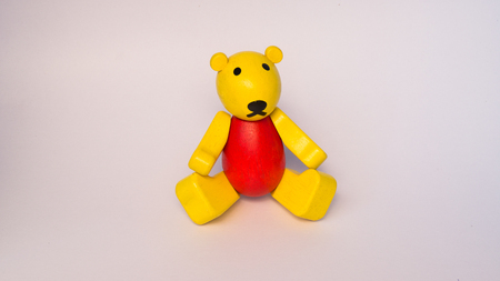 red and yellow wood toy bear with isolated on whiteの写真素材