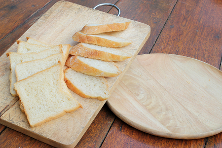 Sliced white bread and French bread baguette on wooden boardの写真素材