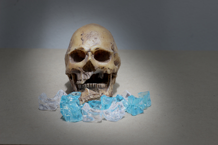 decayed teeth human skull with candy on wood background. like a people eating candy too much.の写真素材