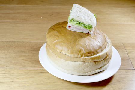 Sandwich box with chicken burger, tomatoes, ham, tuna, cheese on wood table.の写真素材